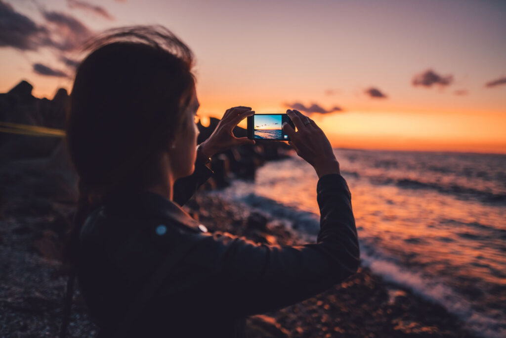 foto maken met smartphone van oceaan bij zonsondergang