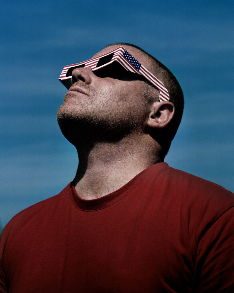 man kijkt naar de zon met donkere bril met Amerikaanse vlag