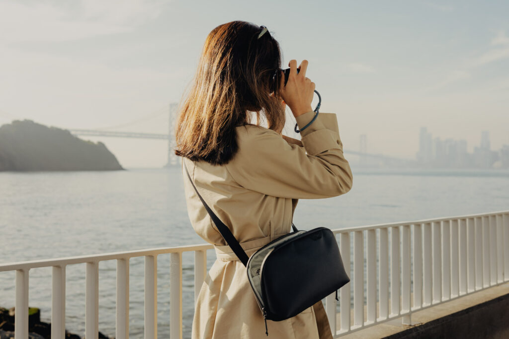 vrouw draagt Peak Design Cross Body tas en maakt een foto met compact camera