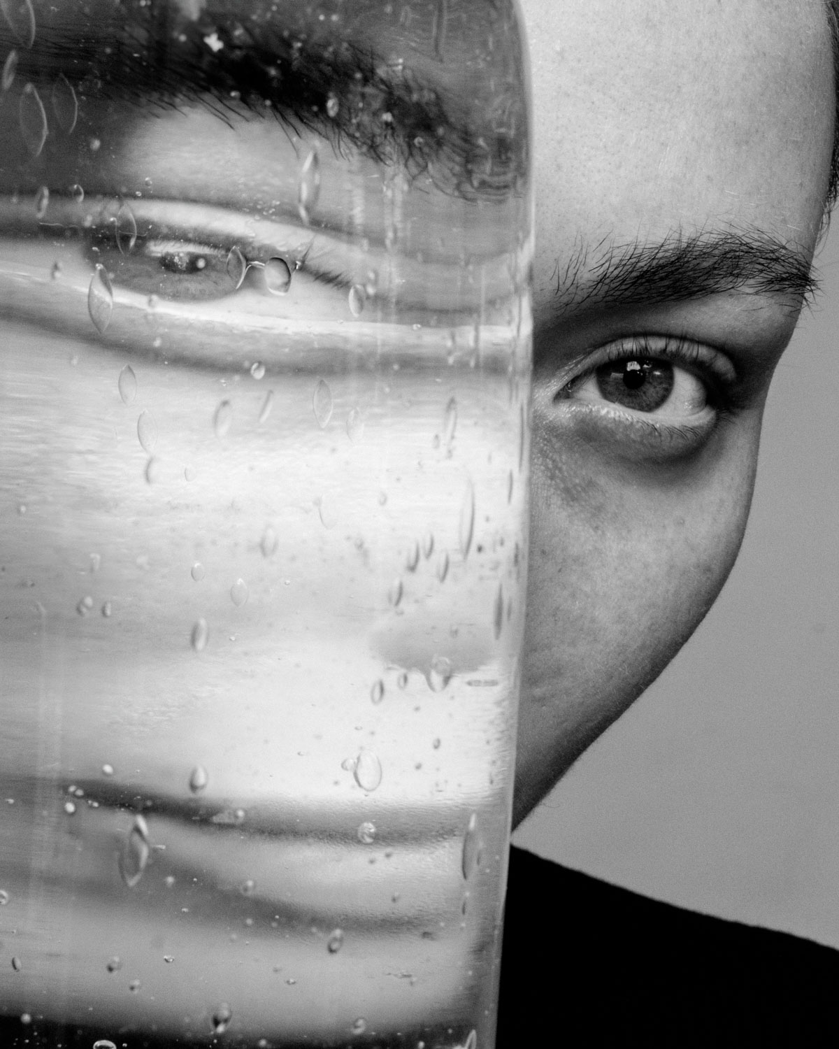 zwart-wit fine art portret door Nanda Hagenaars van gezicht gereflecteerd in glazen ruit