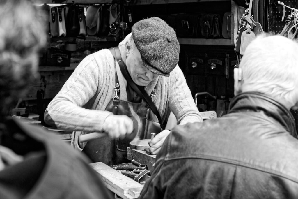 lederwerker met een hamer zwart wit beeld