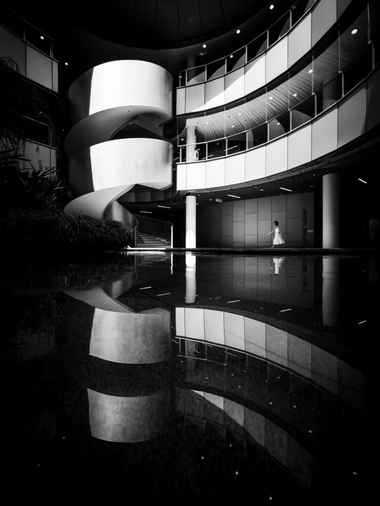 fine art straatfotografie vrouw in wit architecturaal interieur zwart-wit compositie