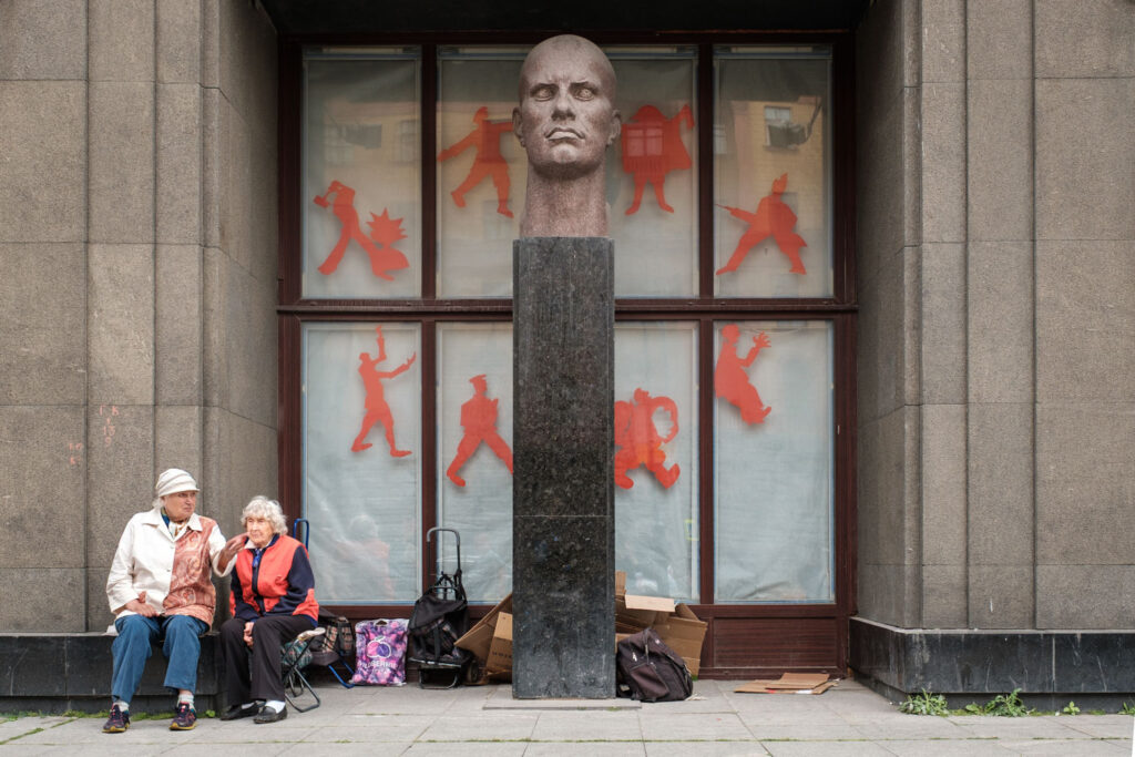Twee oudere mensen rusten bij een standbeeld, sfeerbeeld voor straatfotografie op reis