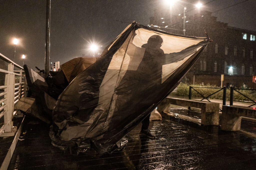 Persfotografie van een vluchteling met een tentje in de regen bij het Klein Kasteeltje in Brussel