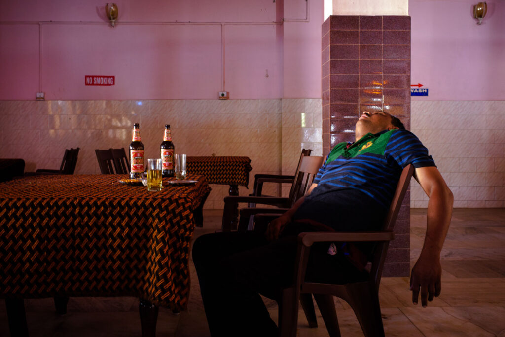 Onherkenbaar gefotografeerde slapende man in een bar, voorbeeld van waardig fotograferen op reis