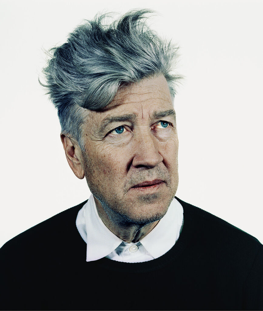 Portret van David Lynch tegen een neutrale achtergrond, zijdelings kijkend.