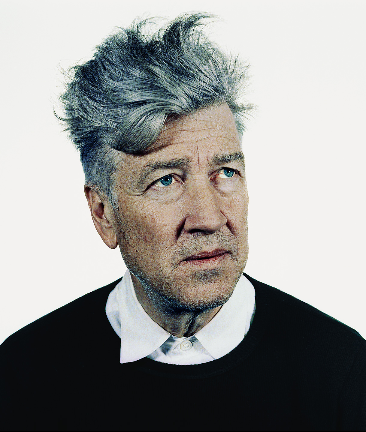 Portret van David Lynch tegen een neutrale achtergrond, zijdelings kijkend.