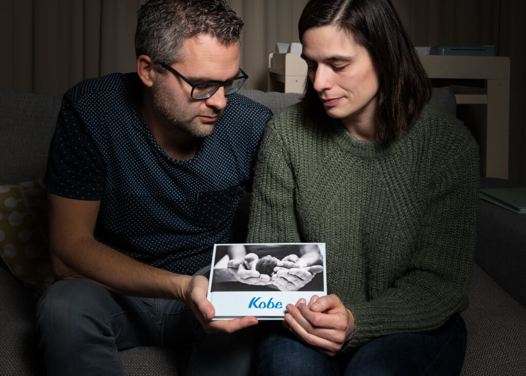 sociaal geëngageerde fotografie van een koppel met een herinneringskaartje van hun overleden kindje