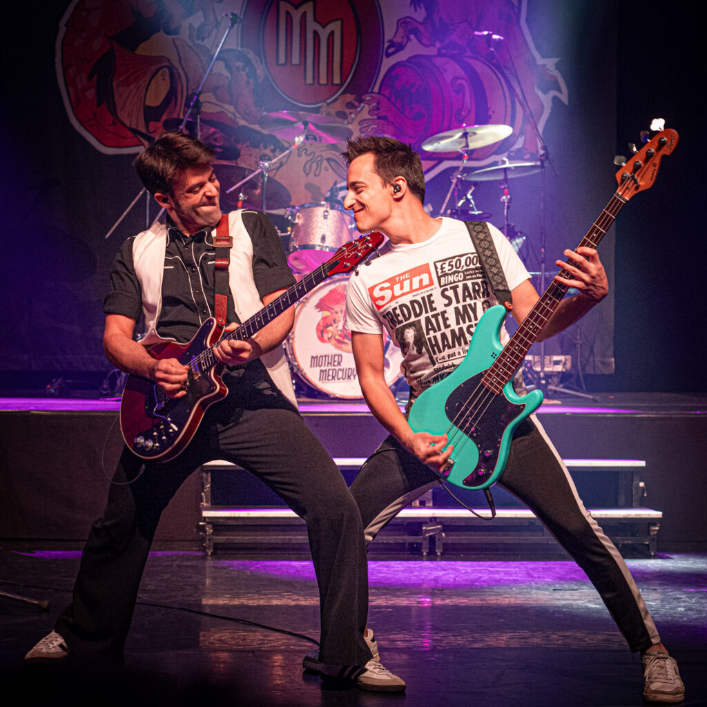 Concertfotografie van twee gitaristen in gekleurd podiumlicht tijdens een lichtshow