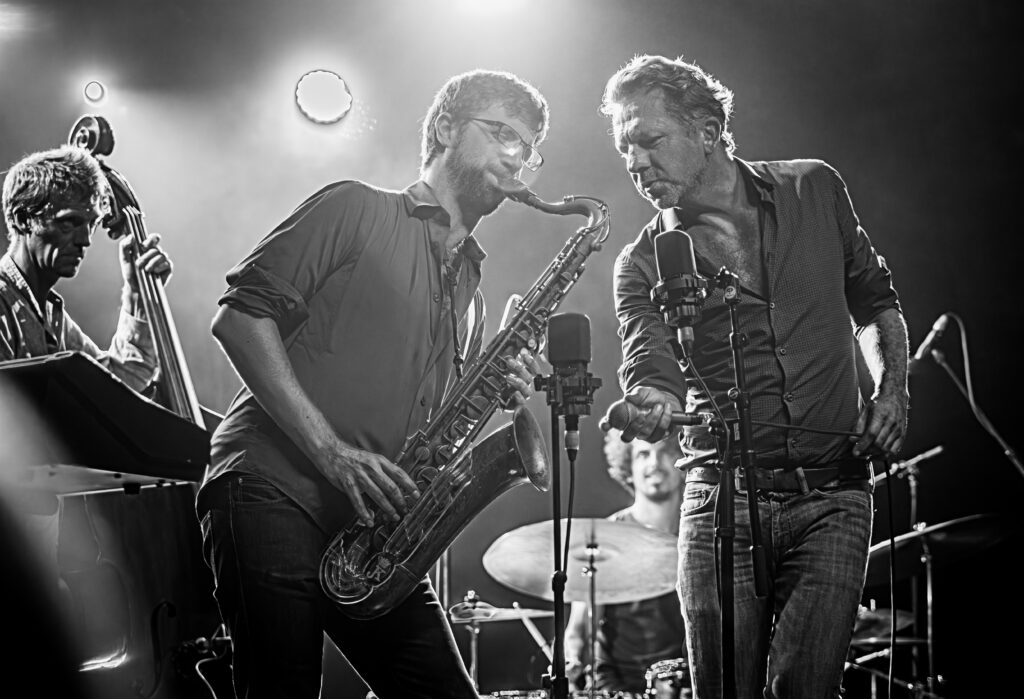 Zwart-wit concertfotografie van Tom Barman en saxofonist Robin Verheyen tijdens een TaxiWars optreden