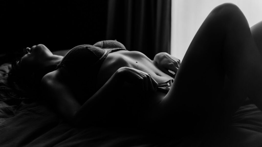 Kunstige boudoirfotografie in low-key van een liggende vrouw op bed
