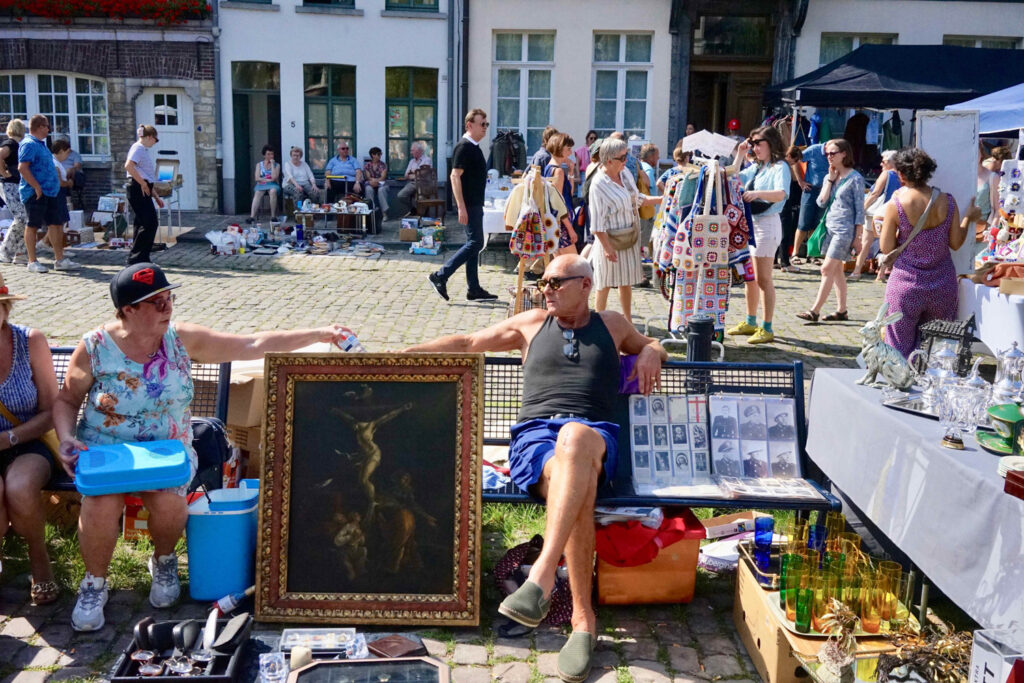 Man en vrouw zitten naast een schilderij op de rommelmarkt