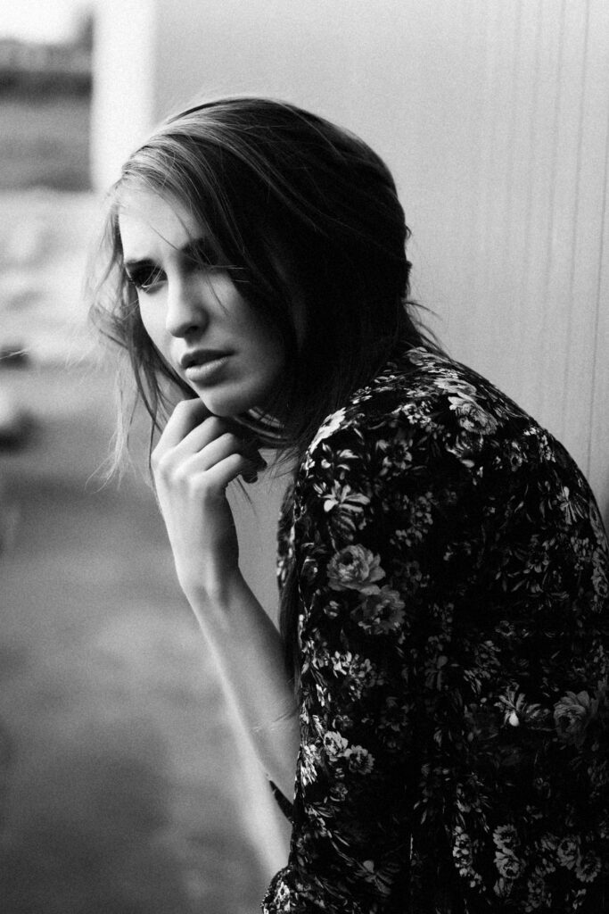 Zwart-wit portretfotografie met natuurlijk licht van een vrouw in gebloemde blouse