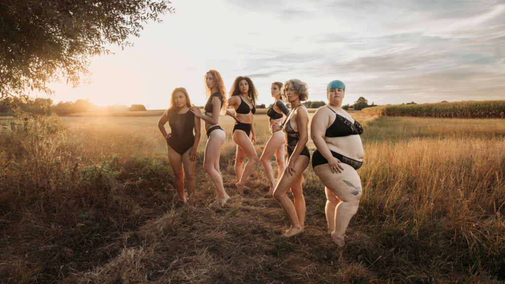 Groepsboudoirshoot van zeven vrouwen met verschillende lichamen bij zonsondergang