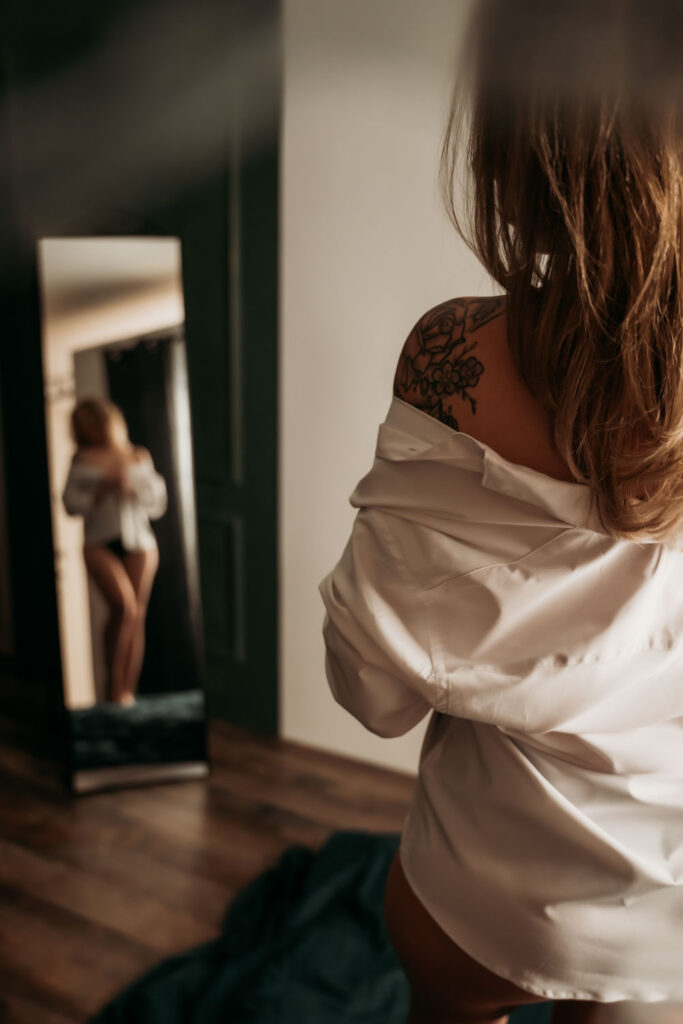 Boudoirfotoshoot van een vrouw met schoudertattoo voor een spiegel