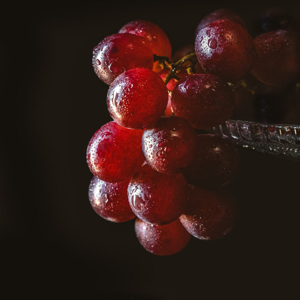 Macro foodfotografie van rode druiven met waterdruppels tegen een donkere achtergrond