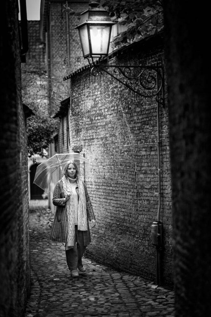 model in klein straatje met doorzichtige paraplu