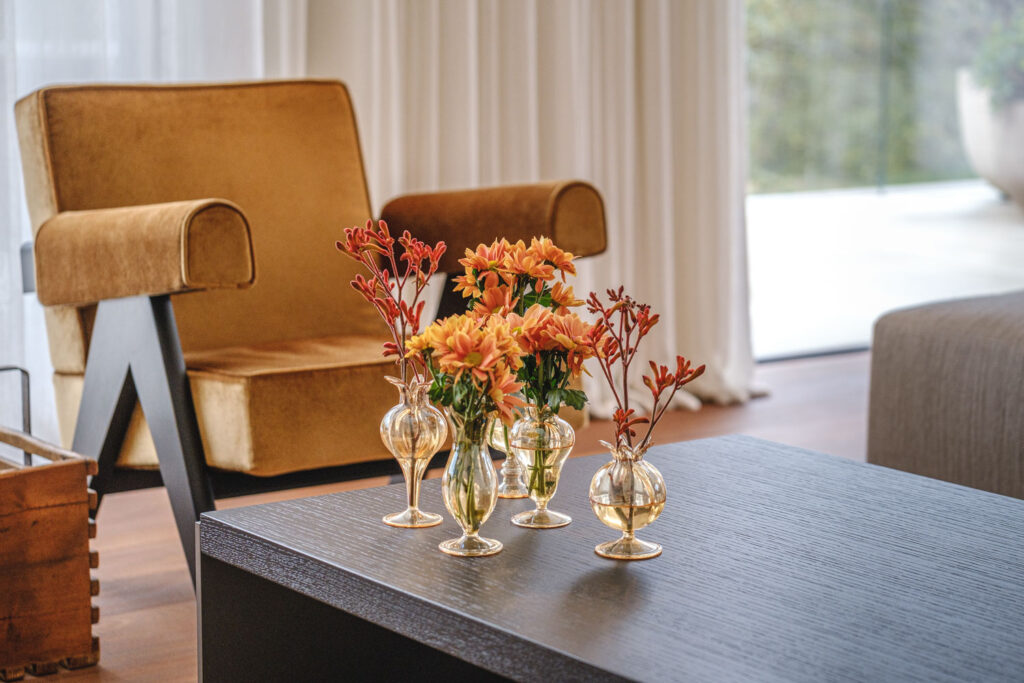 Sfeervolle productfotografie van een okergele fauteuil met bloemen op tafel