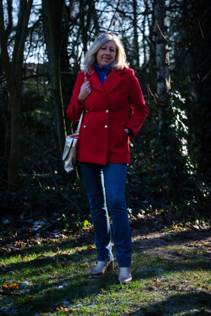 Vrouw in rode jas in het bos, omgeving belicht zonder reportageflitser