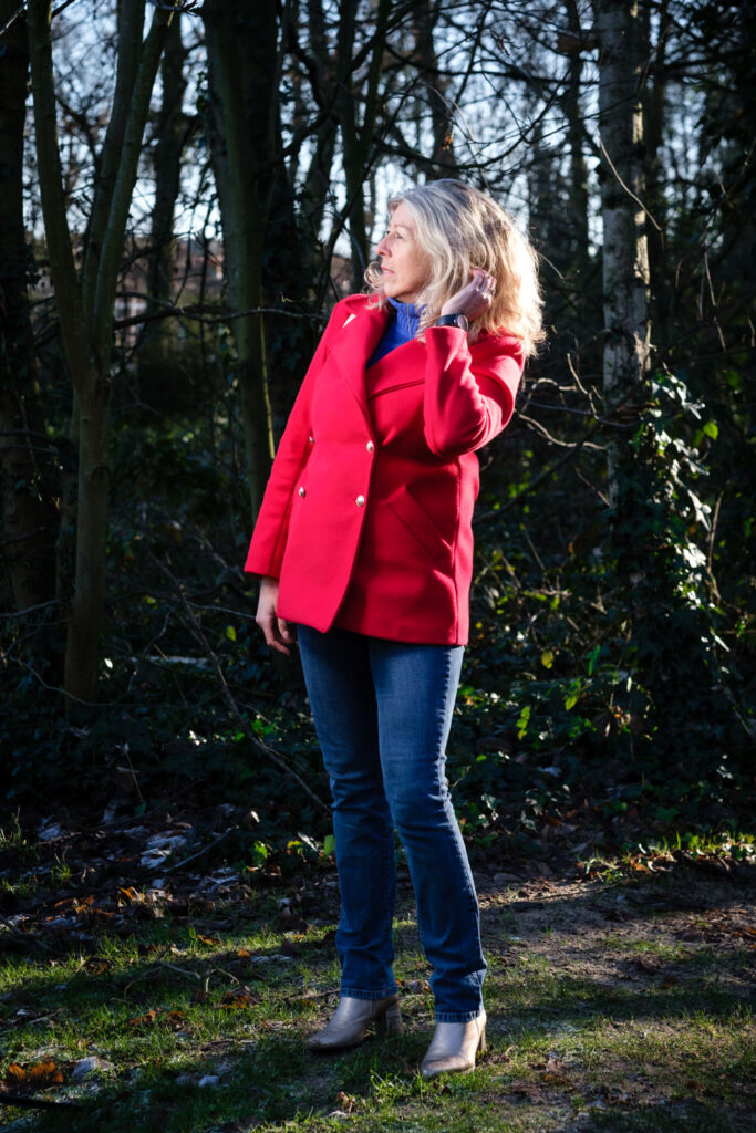 Vrouw in rode jas in het bos, omgeving belicht met reportageflitser
