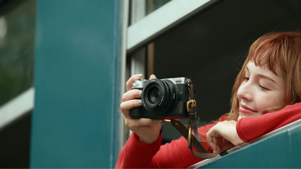 Nikon Z5IIC in handen van vrouw met rode trui