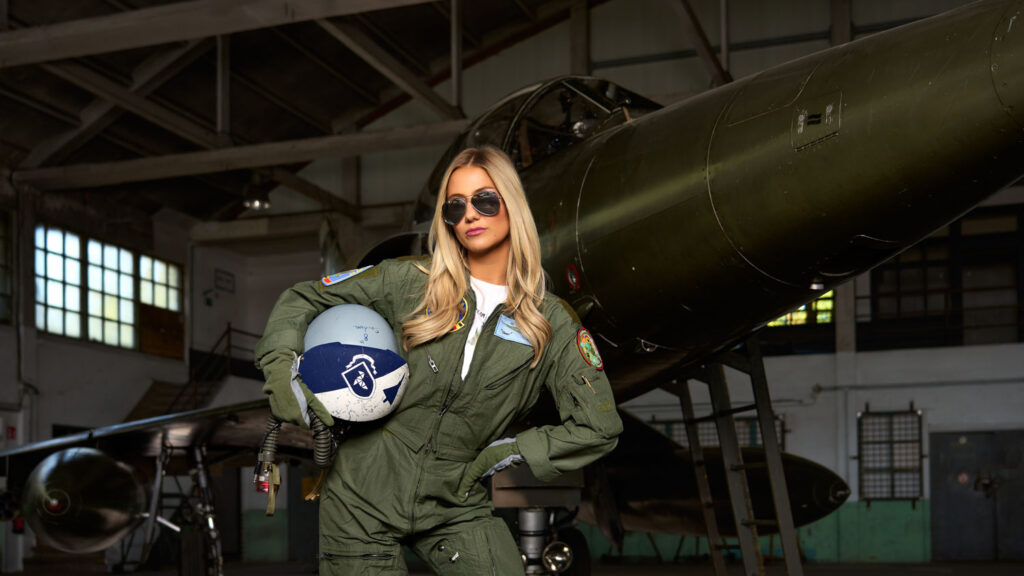 Fashionfotografie op locatie met een model in pilotenstijl bij een vliegtuig