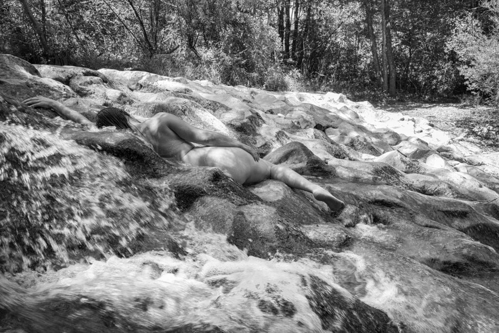 Artistiek naakt van een model tussen rotsen in een Franse rivier, zwart-wit, Staf Devriese