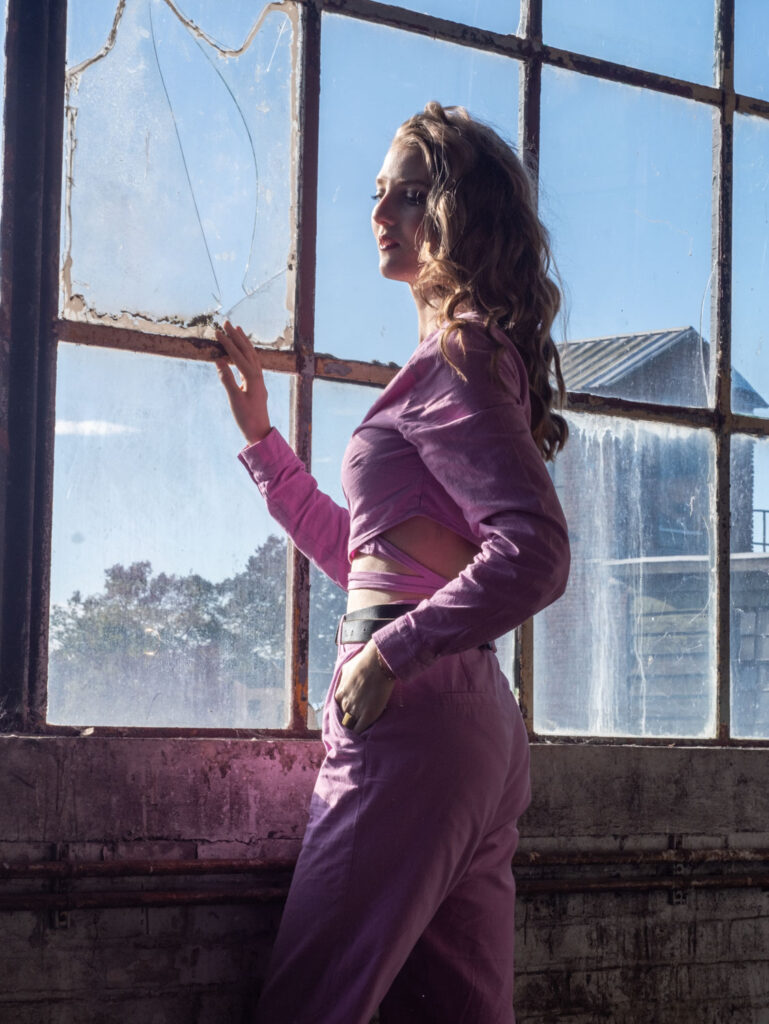 model in roze outfit voor raam
