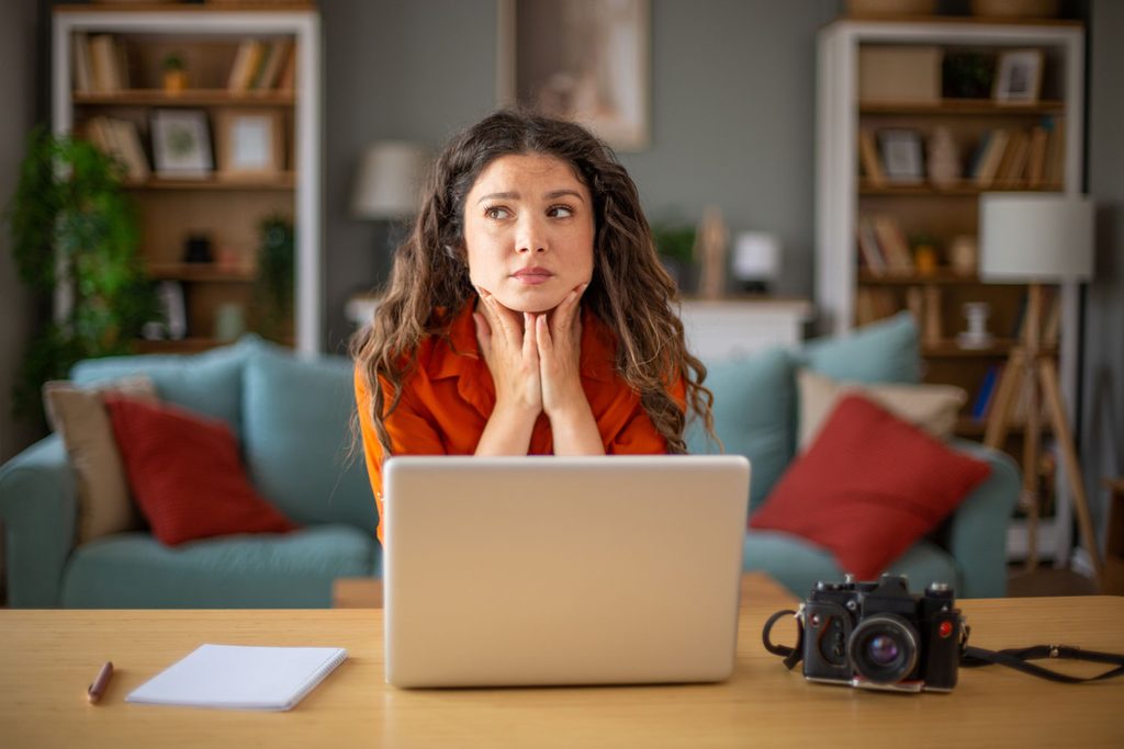 jonge fotografe zit verbaasd achter laptop